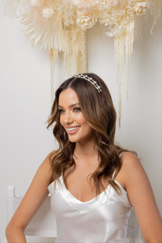 A woman in a white dress  with a double row pearl headband