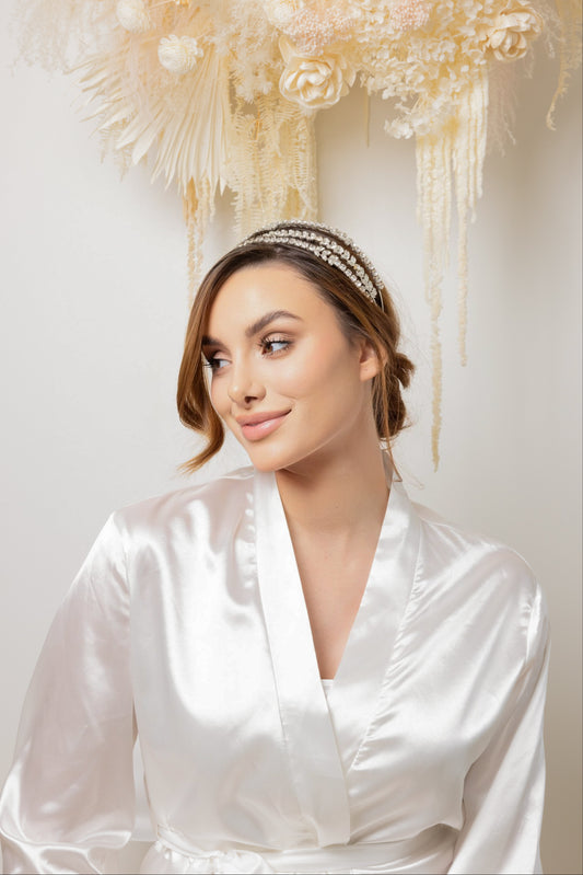 A woman in a white robe and an elegant headband adorned with cubic zirconia